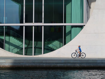 Boy riding bicycle in front of glass window of building