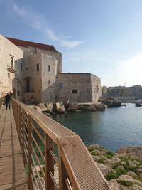 Bridge over sea by buildings against sky