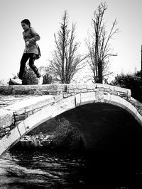 Rear view of boy standing by canal against trees