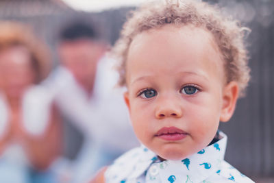 Mixed race boy with blue eyes looking at camera and parents on back