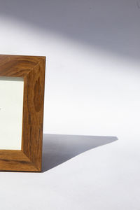 Close-up of wooden table against white wall