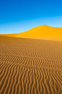 Scenic view of desert against clear blue sky