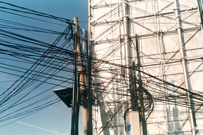 Low angle view of electricity pylon against blue sky