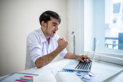 Young man using phone while sitting on table