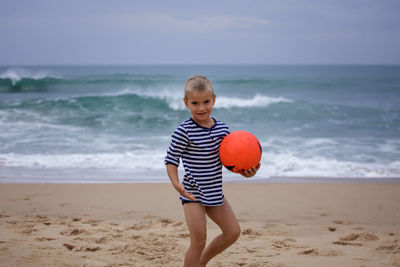 Young soccer player plays barefoot on the ocean shore. football, sport, passion. active lifestyle