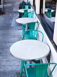 Empty chairs and tables at sidewalk cafe