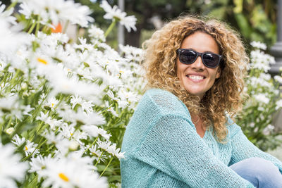 Portrait of young woman wearing sunglasses while standing against trees