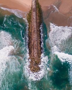 Aerial view of a majestic breakwater with rough rolling water waves rolling, setubal, portugal.