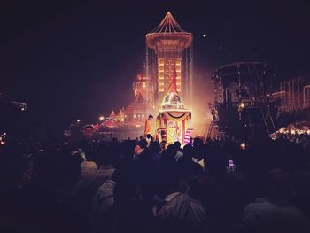 People at illuminated building in city at night