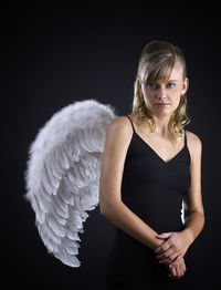 Portrait of young woman against black background