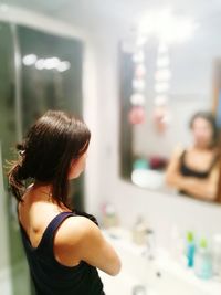 Woman reflecting on mirror in bathroom at home