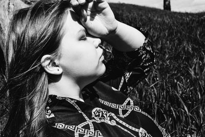 Portrait of young woman looking away while relaxing on field