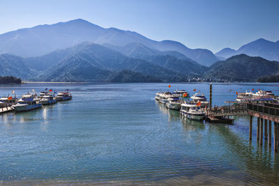 Boats moored at harbor against clear sky