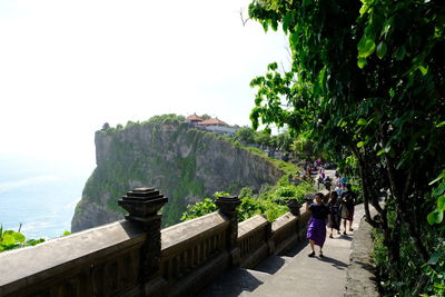 People walking on mountain road against sky