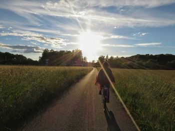 Rear view of people riding bicycle on field