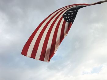 Low angle view of american flag waving against sky