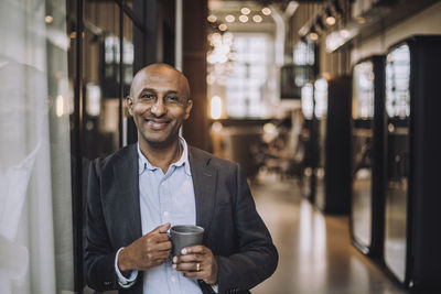 Portrait of bald businessman with coffee mug in creative office