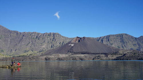 Scenic view of lake and mountains against clear blue sky