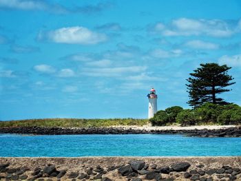 Lighthouse by sea against sky