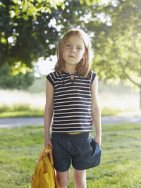 Girl with backpack standing in park