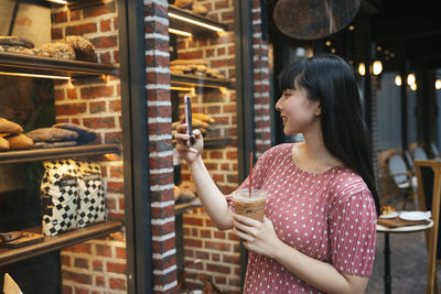 Side view of young woman drinking glass at store