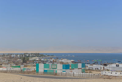 High angle view of buildings by sea against clear blue sky