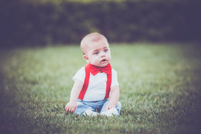 Cute boy sitting on grassy field