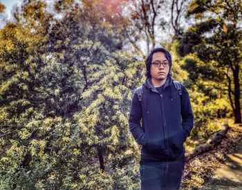 Portrait of young asian man standing in the woods.