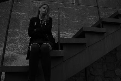 Low angle view of woman sitting on steps against wall