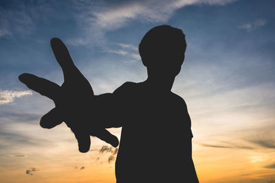 Silhouette man gesturing against sky during sunset