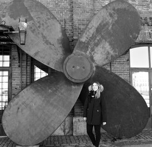 Midsection of woman holding umbrella standing against wall