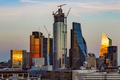 Modern buildings in city against sky during sunset