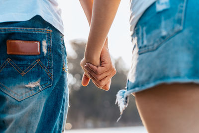 Midsection of couple holding hands outdoors