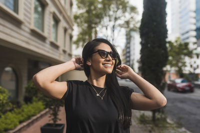 Portrait of young woman wearing sunglasses standing in city