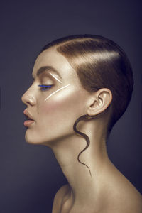 Close-up of young woman with make-up against blue background