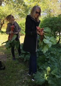 Full length of woman with arms outstretched standing against plants