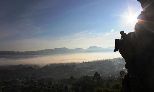 Silhouette of person sitting on cliff