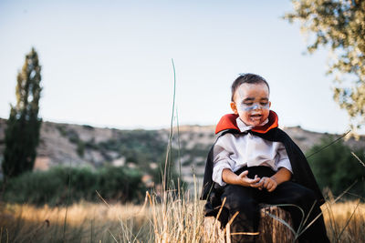 Full length of boy sitting on field against sky