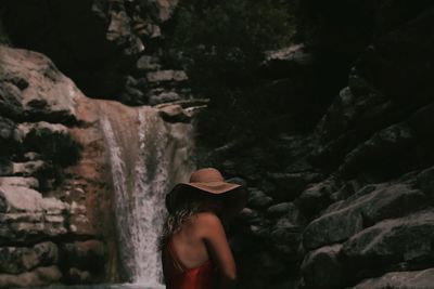 Side view of woman standing against waterfall