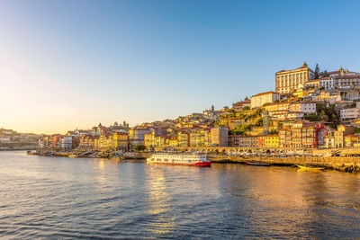 Buildings by sea against clear sky
