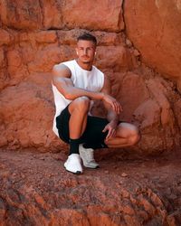 Full length of young man sitting on rock