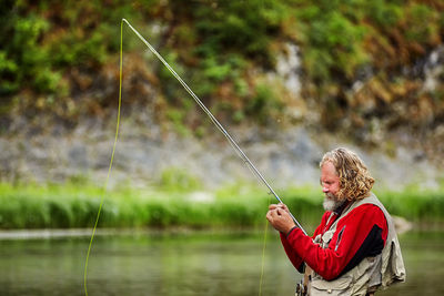 Man holding fishing rod by lake