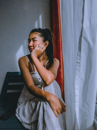 Smiling woman looking away while sitting at home