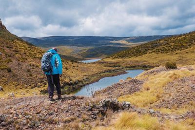Rear view of a hiker against a mountain background at  lake ellis in chogoria route, mount kenya