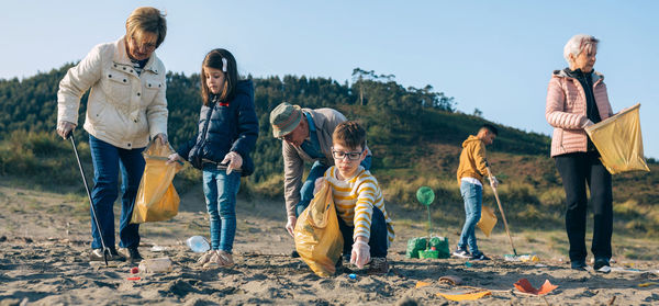 Family cleaning beach against sky