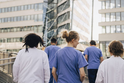 Rear view of female healthcare colleagues walking towards hospital