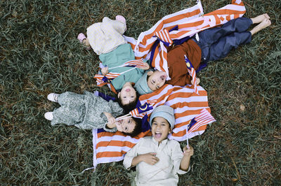 Directly above shot of friends with malaysian flags lying in park