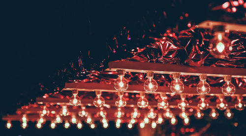 Low angle view of illuminated lights bulbs on ceiling