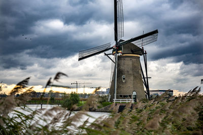 Low angle view of traditional windmill on field against sky