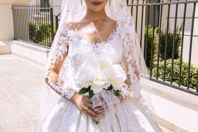 Midsection of bride holding bouquet